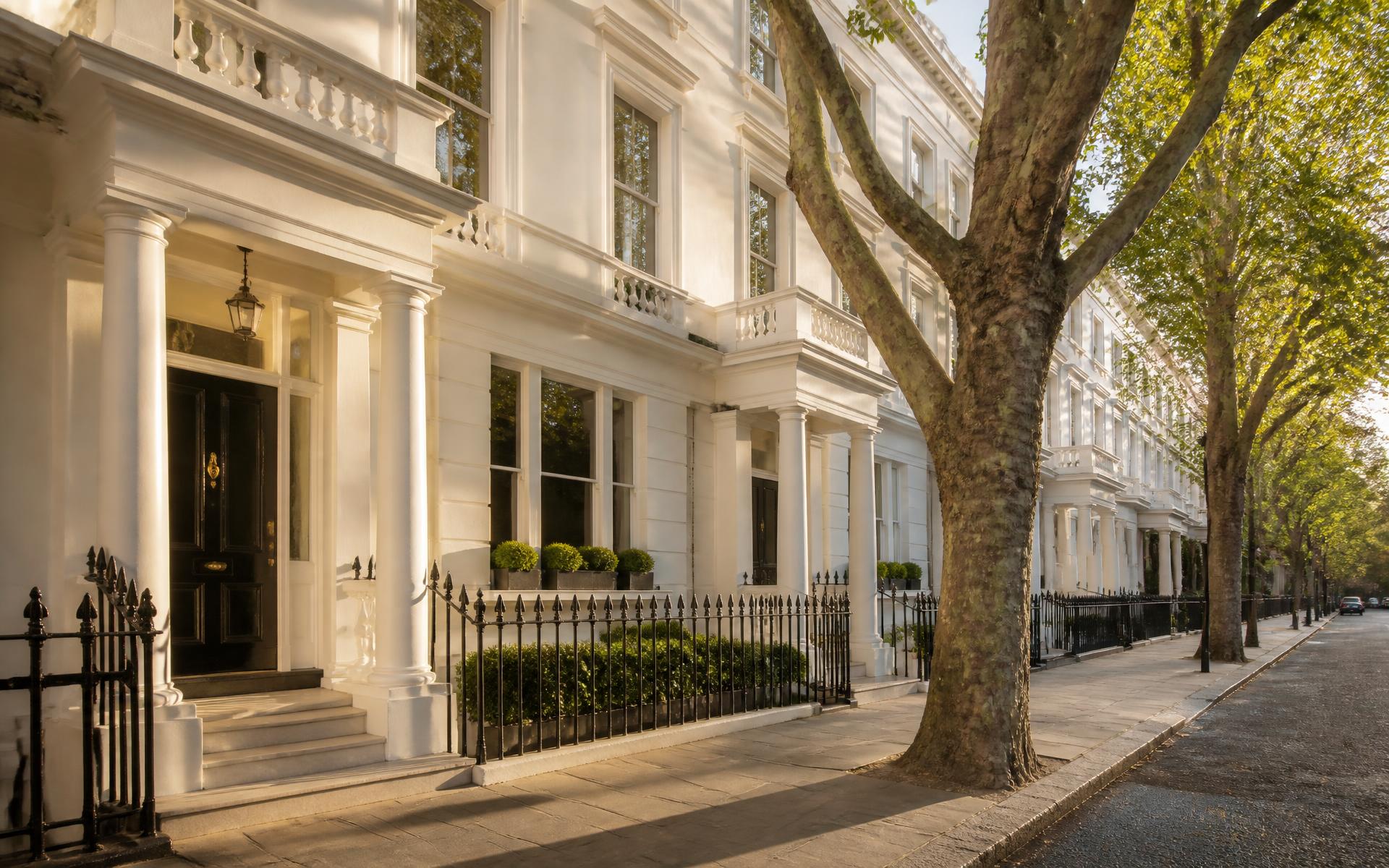 White stucco period terrace houses on a tree-lined prime London street